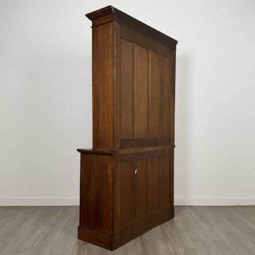 fig 5. A Victorian golden oak two-part glazed bookcase featuring geometric astragal glazing, a dentil cornice, two drawers, and a panelled base cupboard.