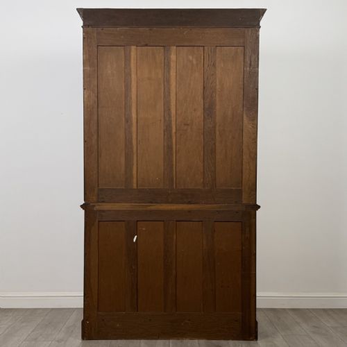 fig 6. A Victorian golden oak two-part glazed bookcase featuring geometric astragal glazing, a dentil cornice, two drawers, and a panelled base cupboard.