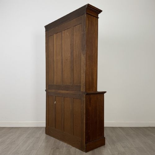 fig 7. A Victorian golden oak two-part glazed bookcase featuring geometric astragal glazing, a dentil cornice, two drawers, and a panelled base cupboard.