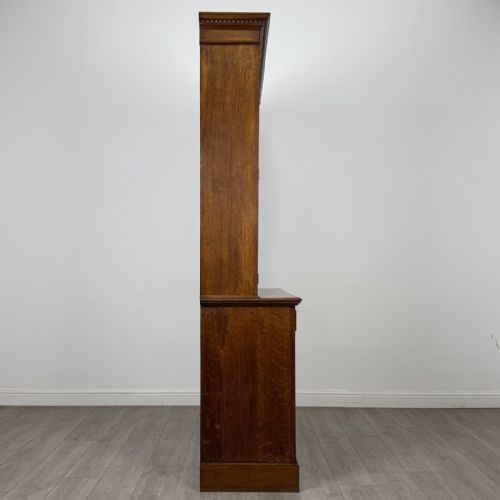 fig 8. A Victorian golden oak two-part glazed bookcase featuring geometric astragal glazing, a dentil cornice, two drawers, and a panelled base cupboard.
