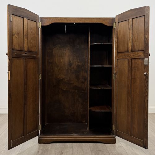 fig 1. A tall dark brown oak double wardrobe featuring hand-carved Gothic tracery panels on top and vertical panel detail below.