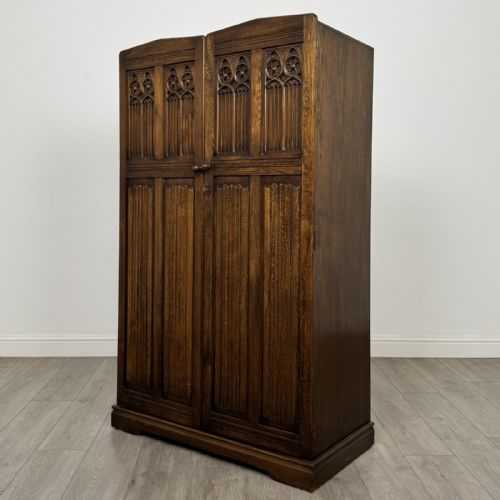 fig 2. A tall dark brown oak double wardrobe featuring hand-carved Gothic tracery panels on top and vertical panel detail below.