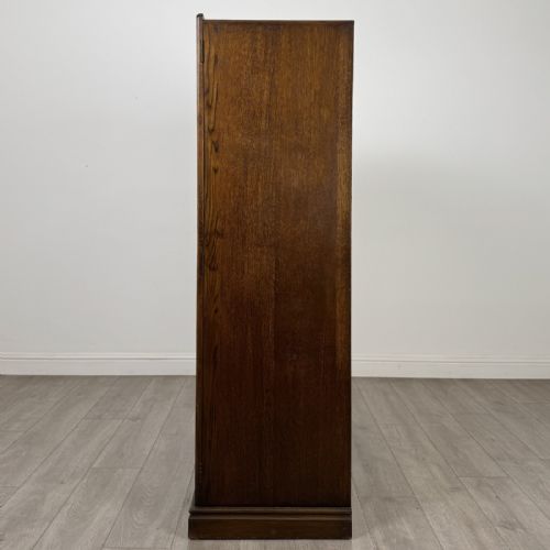 fig 3. A tall dark brown oak double wardrobe featuring hand-carved Gothic tracery panels on top and vertical panel detail below.