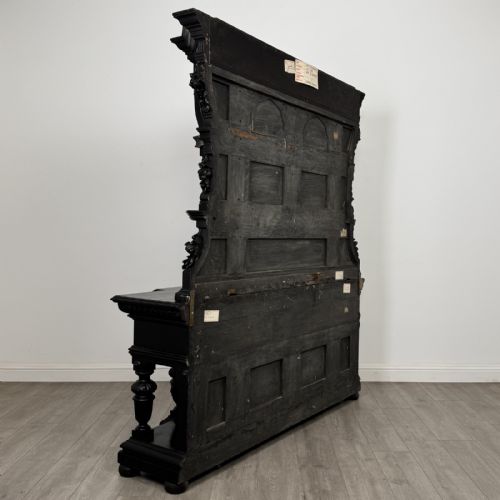fig 3. An ornate ebonised dark wood Victorian sideboard featuring upper tier shelves with carved arches, lion masks, and lower drawers with brass drop handles.