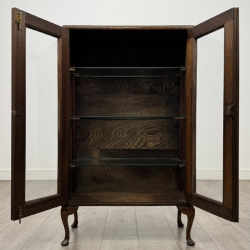 fig 1. An antique Edwardian mahogany display cabinet featuring twin glazed doors, glass interior shelving, and cabriole legs.