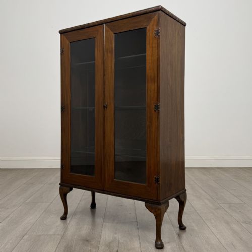 fig 2. An antique Edwardian mahogany display cabinet featuring twin glazed doors, glass interior shelving, and cabriole legs.
