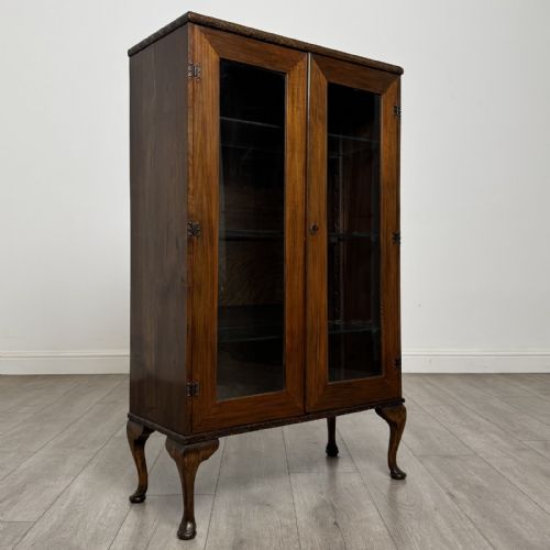 fig 8. An antique Edwardian mahogany display cabinet featuring twin glazed doors, glass interior shelving, and cabriole legs.