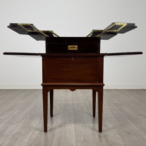 fig 2. A 19th-century mahogany fold-out cabinet standing on four square tapered legs with a brass keyhole escutcheon on the front casing.