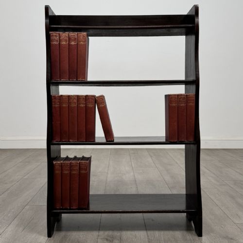 fig 1. A dark brown Edwardian oak open bookcase featuring four open shelf tiers and shaped side panels.