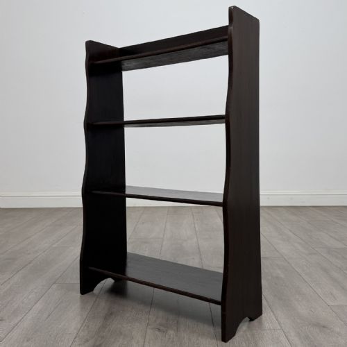 fig 2. A dark brown Edwardian oak open bookcase featuring four open shelf tiers and shaped side panels.
