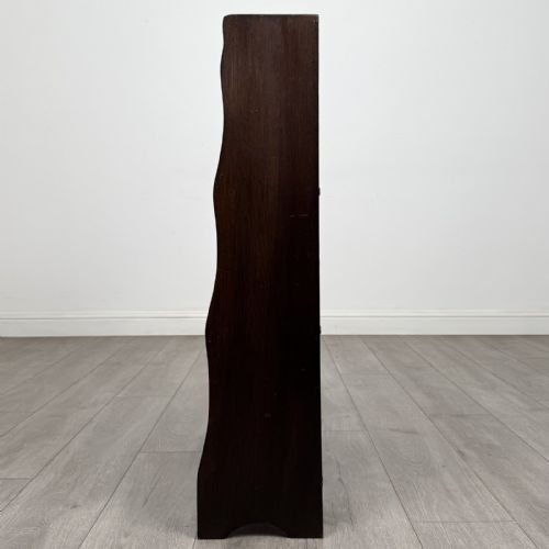 fig 3. A dark brown Edwardian oak open bookcase featuring four open shelf tiers and shaped side panels.