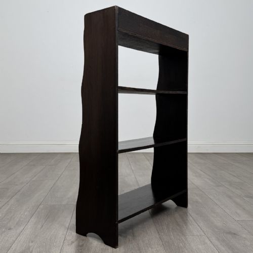 fig 4. A dark brown Edwardian oak open bookcase featuring four open shelf tiers and shaped side panels.