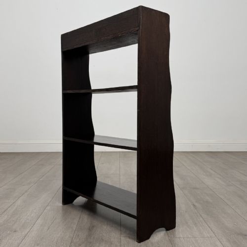 fig 6. A dark brown Edwardian oak open bookcase featuring four open shelf tiers and shaped side panels.