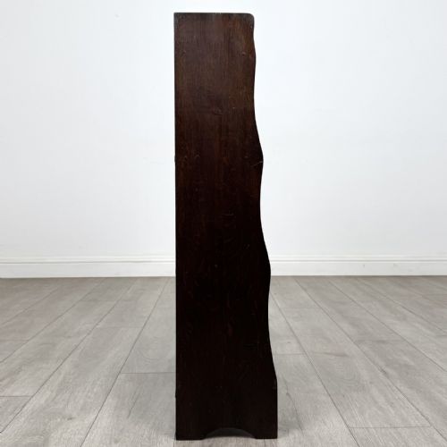 fig 7. A dark brown Edwardian oak open bookcase featuring four open shelf tiers and shaped side panels.