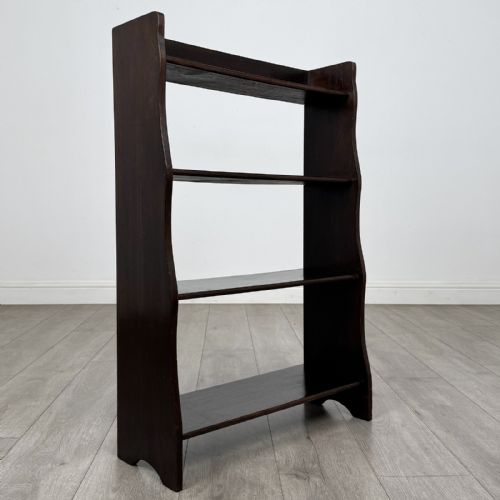 fig 8. A dark brown Edwardian oak open bookcase featuring four open shelf tiers and shaped side panels.