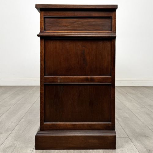 fig 3. A dark oak sideboard featuring three drawers above three cupboard doors decorated with carved floral and arcaded panels and ornamental drop handles.