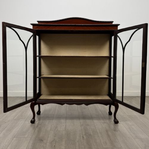 fig 1. An Edwardian dark mahogany display cabinet with twin astragal glazed doors, fabric-lined interior shelves, and cabriole legs with carved claw and ball feet.