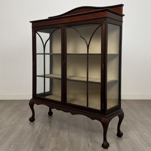 fig 2. An Edwardian dark mahogany display cabinet with twin astragal glazed doors, fabric-lined interior shelves, and cabriole legs with carved claw and ball feet.