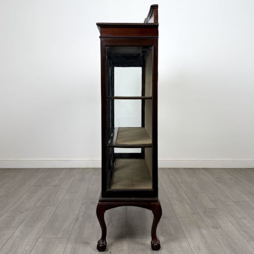 fig 3. An Edwardian dark mahogany display cabinet with twin astragal glazed doors, fabric-lined interior shelves, and cabriole legs with carved claw and ball feet.