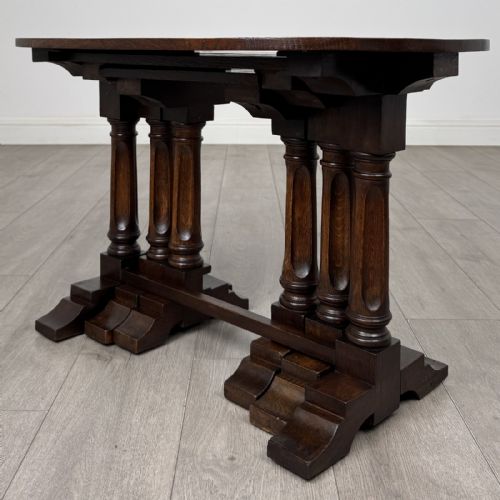 fig 1. A set of three nesting dark oak occasional tables featuring turned baluster legs and trestle feet.