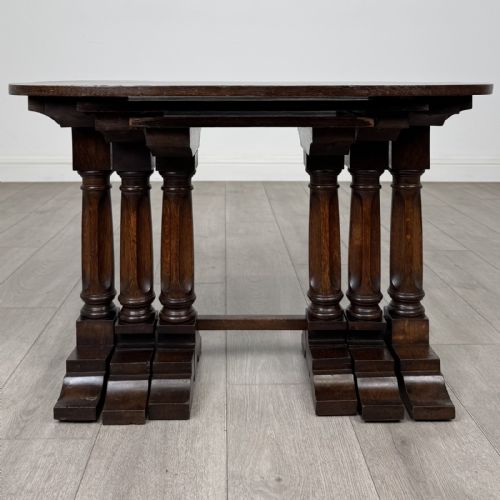 fig 3. A set of three nesting dark oak occasional tables featuring turned baluster legs and trestle feet.