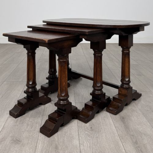 fig 4. A set of three nesting dark oak occasional tables featuring turned baluster legs and trestle feet.