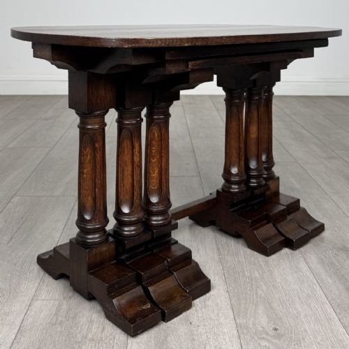 fig 8. A set of three nesting dark oak occasional tables featuring turned baluster legs and trestle feet.