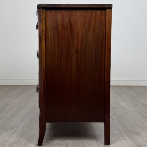 fig 2. A dark mahogany bow-fronted chest of drawers featuring brass oval ring handles, reeded side columns, and curved legs.