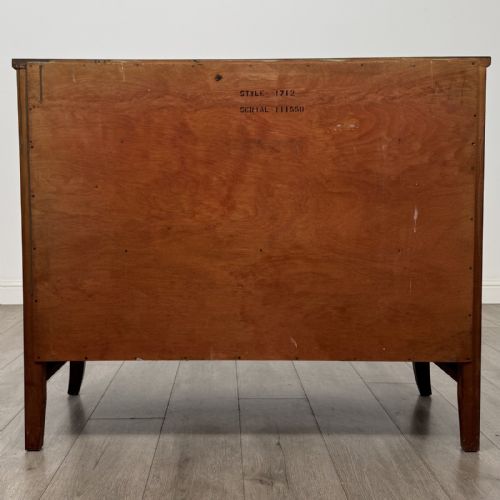 fig 4. A dark mahogany bow-fronted chest of drawers featuring brass oval ring handles, reeded side columns, and curved legs.