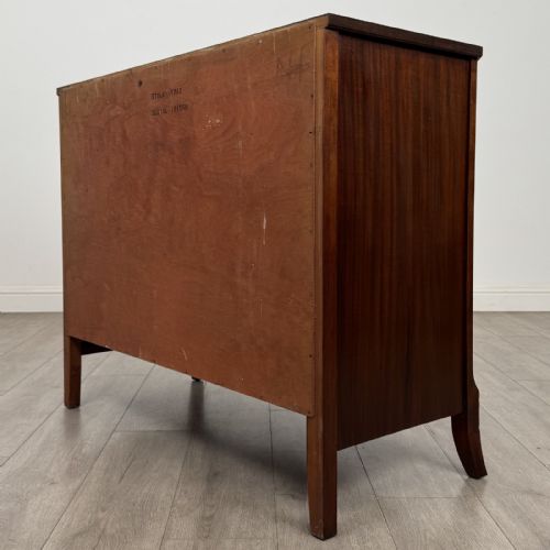 fig 5. A dark mahogany bow-fronted chest of drawers featuring brass oval ring handles, reeded side columns, and curved legs.