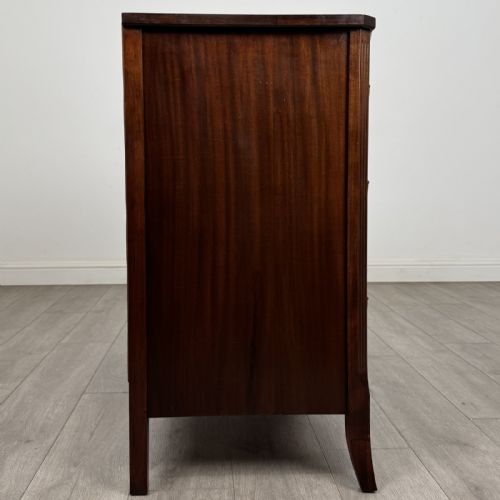 fig 6. A dark mahogany bow-fronted chest of drawers featuring brass oval ring handles, reeded side columns, and curved legs.