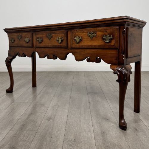 fig 1. A Queen Anne style elm dresser base featuring three drawers with brass handles, a shaped apron, and cabriole legs ending in pad feet.
