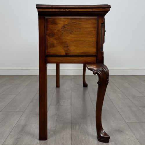 fig 6. A Queen Anne style elm dresser base featuring three drawers with brass handles, a shaped apron, and cabriole legs ending in pad feet.