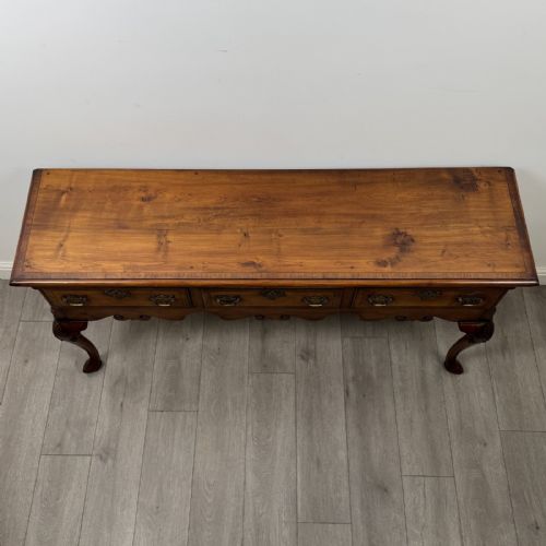 fig 8. A Queen Anne style elm dresser base featuring three drawers with brass handles, a shaped apron, and cabriole legs ending in pad feet.