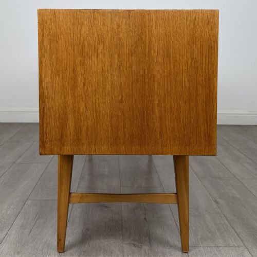 fig 2. A mid-century oak sideboard featuring six wide drawers with circular wooden pull knobs, supported by tapered legs and side stretchers.