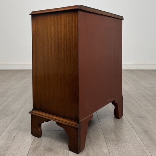 fig 3. A small antique mahogany bow front chest featuring three drawers with brass ring drop handles resting on bracket feet.