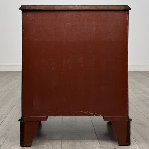 fig 4. A small antique mahogany bow front chest featuring three drawers with brass ring drop handles resting on bracket feet.