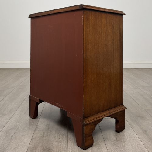 fig 5. A small antique mahogany bow front chest featuring three drawers with brass ring drop handles resting on bracket feet.