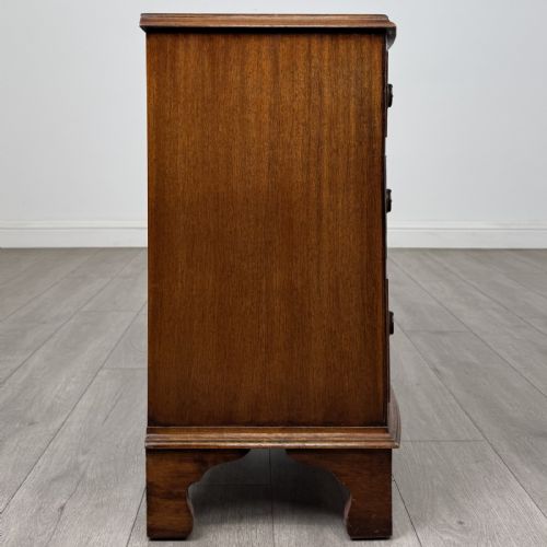 fig 6. A small antique mahogany bow front chest featuring three drawers with brass ring drop handles resting on bracket feet.