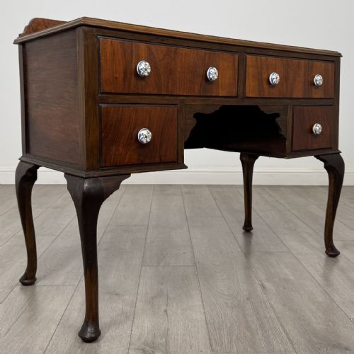 fig 7. An Edwardian walnut writing table featuring four drawers with blue and white patterned ceramic knobs, raised on cabriole legs.