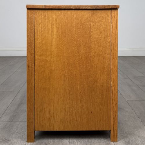 fig 6. A golden oak chest of drawers featuring three horizontal drawers with turned wooden knob handles resting on a shaped apron base.