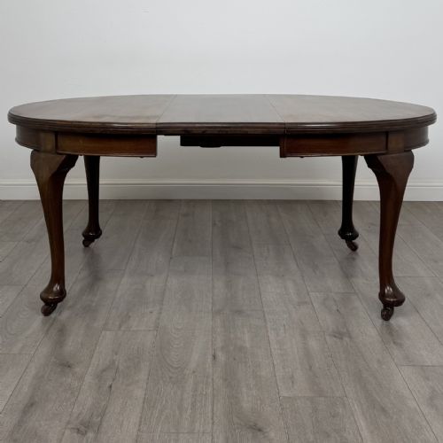 fig 1. An antique Edwardian oval mahogany extending dining table featuring cabriole legs on castors with a removable centre leaf.