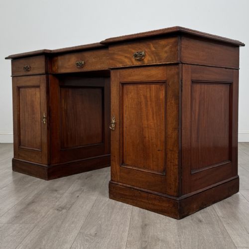 fig 2. A Victorian mahogany twin pedestal desk featuring a breakfront top, three upper frieze drawers, and two panelled cupboard doors on a plinth base.