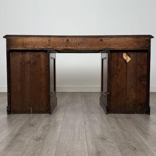 fig 5. A Victorian mahogany twin pedestal desk featuring a breakfront top, three upper frieze drawers, and two panelled cupboard doors on a plinth base.