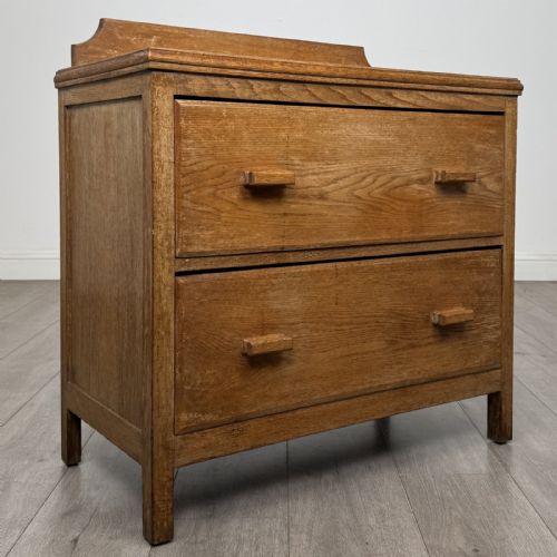 fig 7. An antique golden oak chest of drawers featuring two full-width drawers with matching rectangular wooden handles and a low raised gallery upstand.