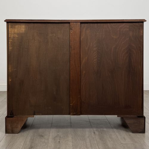 fig 4. A Georgian style mahogany chest of drawers featuring a two-over-three drawer arrangement, brass ring handles, and bracket feet.