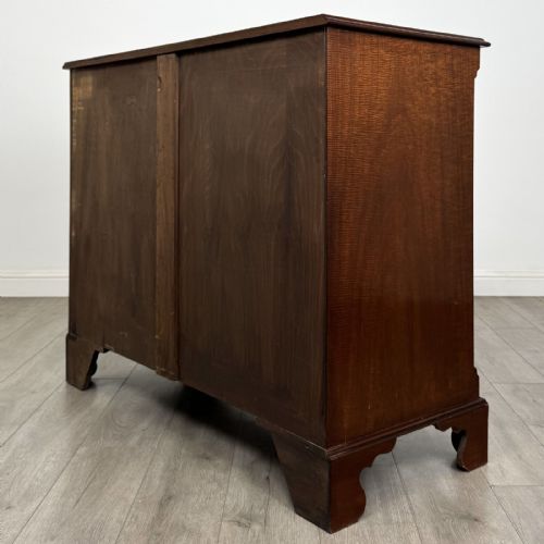 fig 5. A Georgian style mahogany chest of drawers featuring a two-over-three drawer arrangement, brass ring handles, and bracket feet.