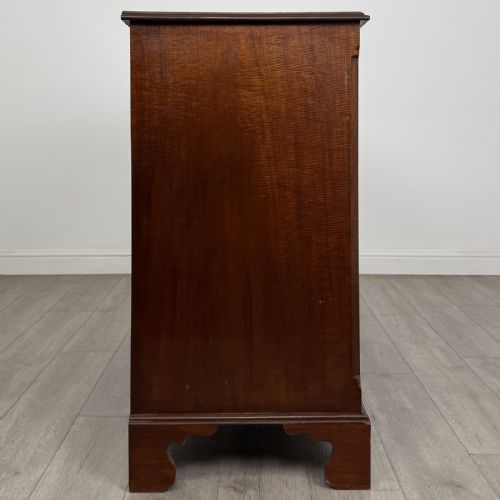 fig 6. A Georgian style mahogany chest of drawers featuring a two-over-three drawer arrangement, brass ring handles, and bracket feet.
