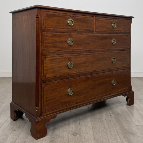 fig 7. A Georgian style mahogany chest of drawers featuring a two-over-three drawer arrangement, brass ring handles, and bracket feet.