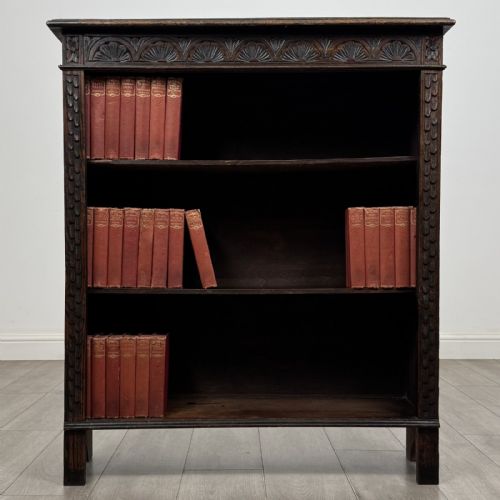 fig 1. A dark brown Victorian carved oak open bookcase with three adjustable shelves and carved decorative borders on the frieze and uprights.